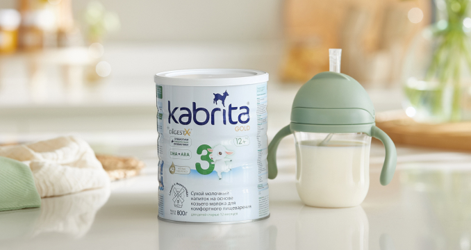 Банка детской смеси Kabrita на козьем молоке рядом с детской бутылочкой