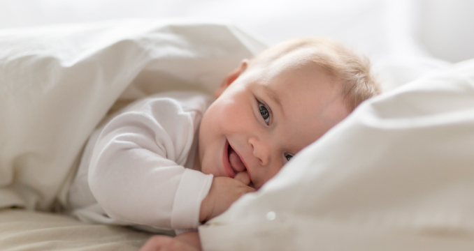 Малыш спит под белым одеялом — крепкий сон укрепляет иммунитет ребенка